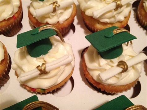 Cupcakes Decorated With White Frosting And Green Graduation Caps Are