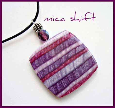 A Purple And Red Striped Glass Pendant With A Bead On A Black Cord Necklace