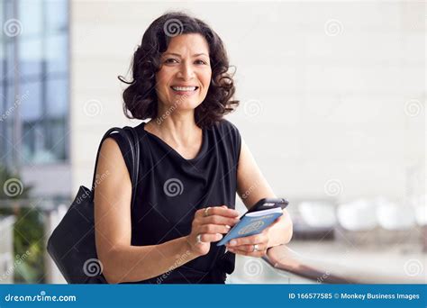 Portrait Of Mature Businesswoman With Passport In Airport Departure