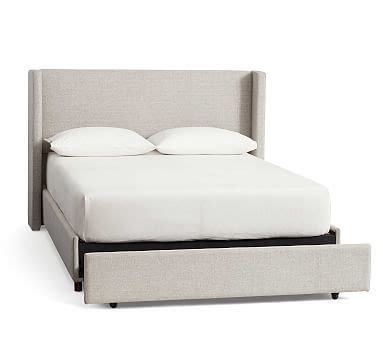 The Bed Is Made Up And Has Two Pillows On Top Of It With An Ottoman