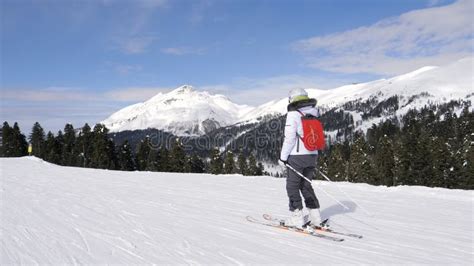 Woman Skier Slides Down Snowy Ski Slope In Mountains With Pine Trees In