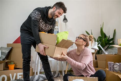 Young Couple Carrying Big Cardboard Box At New Homemoving House Stock