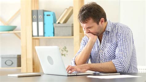 Upset And Frustrated Man Thinking And Working On Laptop Stock Photo