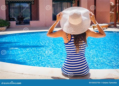 Young Beautiful Woman Enjoying The Sun And Sitting On Edge Of The Pool