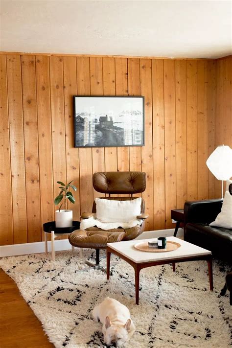 A Living Room With Wood Paneling And Black Leather Chairs White Rugs