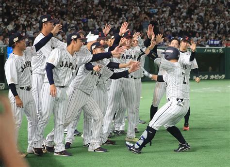 アジアプロ野球チャンピオンシップ決勝の韓国戦10回、送りバントを決めた古賀（右）はチームメートに出迎えられる ― スポニチ Sponichi