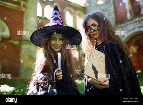 Waist Up Portrait Of Two Little Witches Looking At Camera While Posing