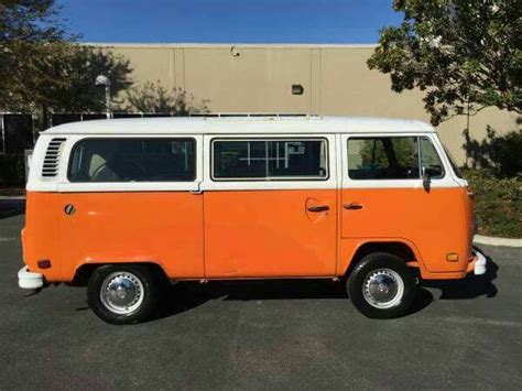 An Orange And White Vw Bus Parked In A Parking Lot Next To A Building