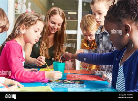 Los Niños Y El Maestro De La Pintura Con Acuarela Y Pincel En La Clase De Pintura En