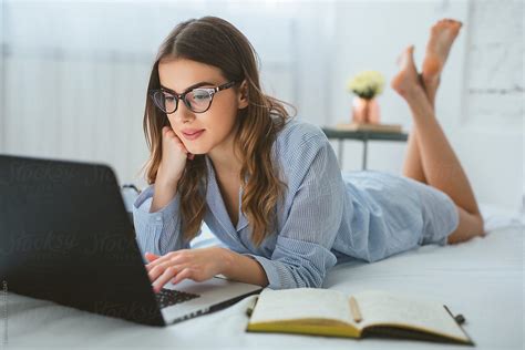 «young Woman Lying In Her Bed And Typing On Laptop Del Colaborador De