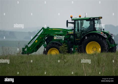 John Deere 6215R Farm Tractor In Motion With Front Lifter Stock Photo