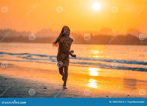 Adorable Happy Little Girl On White Beach At Sunset Stock Photo