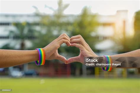 A Young Asian Lgbt Couple Wearing Rainbow Wristbands Put Their Hands