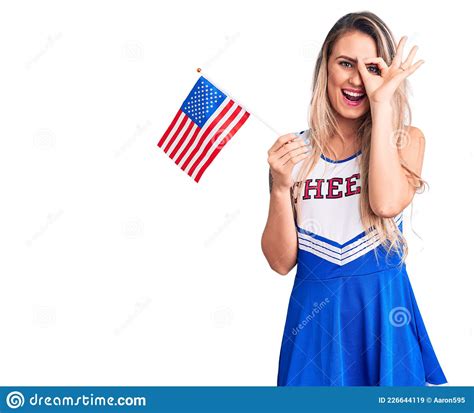 Young Beautiful Blonde Woman Wearing Cheerleader Uniform Holding United