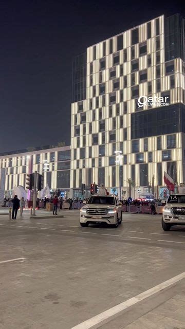 Two Cars Are Driving Down The Street In Front Of A Large Building With