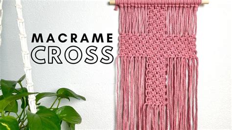 a pink macrame wall hanging next to a potted plant with text overlay reading macrame cross