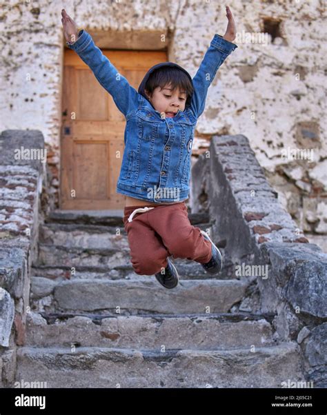 Niño saltando de alegría en una vieja escalera en un pueblo argentino