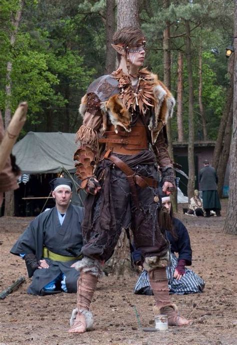 a man dressed up in costume standing next to a tree with other people ...