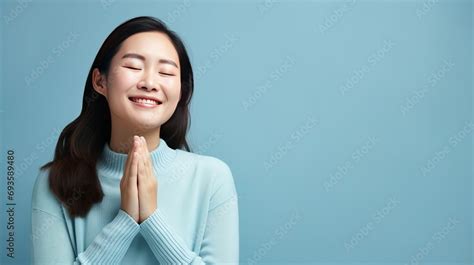 A Beautiful Asian Woman Standing Against A Blue Background Smiles With