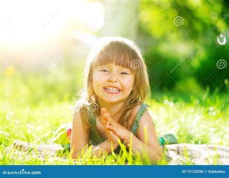 Petite Fille De Sourire Se Trouvant Sur L Herbe Verte Photo Stock