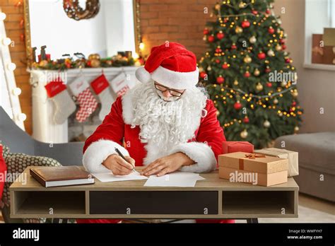 Santa Claus Making List Of Ts In Room Decorated For Christmas Stock