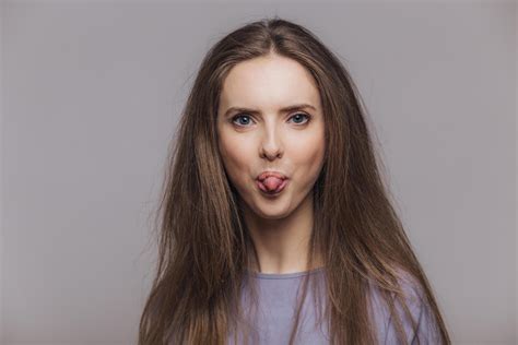 Funny Brunette Female With Atractive Look Shows Tongue Makes Grimace