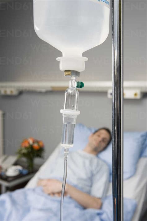 An IV drip and a patient in the background stock photo