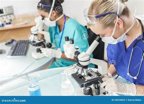 Female Scientific Research Team Using Microscopes In Laboratory Stock