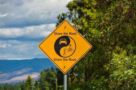 Premium Photo Share The Road Yellow Sign On Green Leaves And Blue Sky