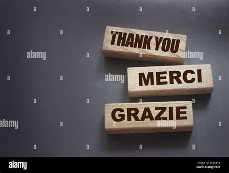 Text Thank You Merci Grazie On Wooden Blocks On Black Background