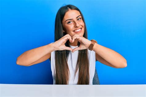 Beautiful Hispanic Woman Wearing Casual Clothes Sitting On The Table