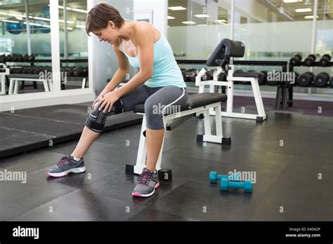 Fit Brunette Sitting On Bench Holding Injured Knee Stock Photo Alamy