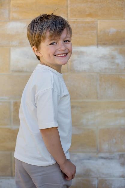 Un niño con una camisa blanca que dice está sonriendo Foto Premium