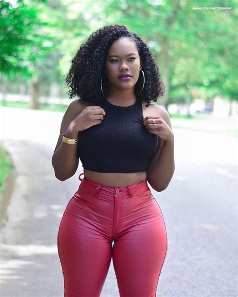 A Woman In High Waisted Red Pants And Black Crop Top Posing For The Camera