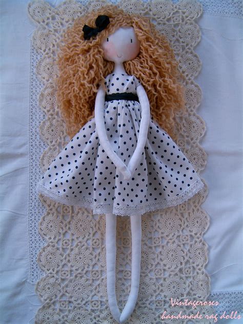 The Doll Is Wearing A White Dress With Black Polka Dots