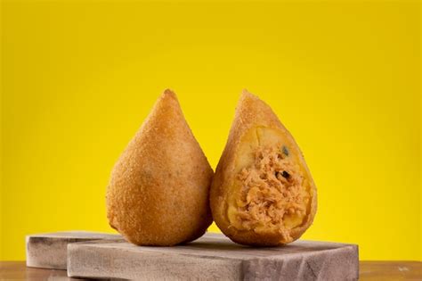 Coxinha frita em tábua de madeira fundo amarelo Foto Premium