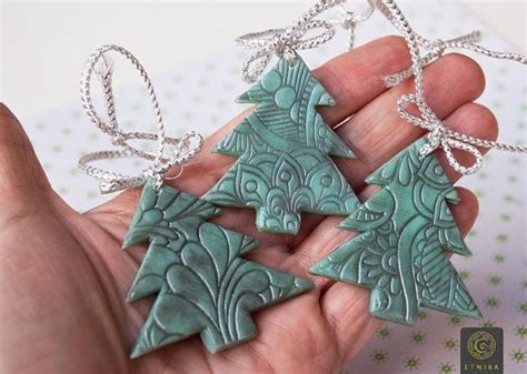 Three Green Ceramic Ornaments In The Shape Of Christmas Trees Are Being