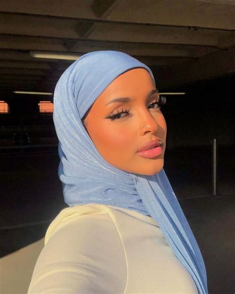 A Woman Wearing A Light Blue Hijab And White Top Looking Off To The Side