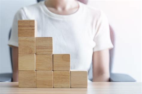 Woman Hand Placing Wood Block On The Building Leadership Business