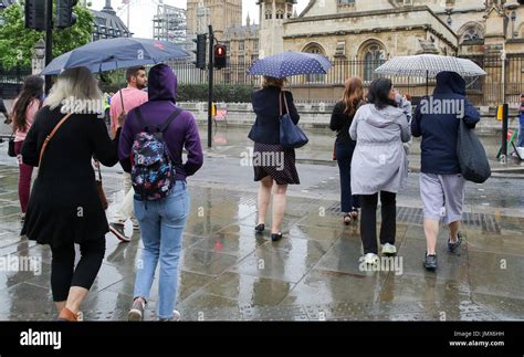 People Take Shelter From The Rain Under Umbrellas In Westminster After