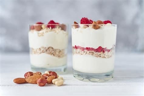 Dos Vidrios De Granola Griego Del Yogur Con Las Frambuesas Las Escamas