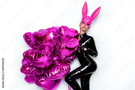 Sexy Blonde Woman Posing In Latex Black Costume And Pink Bunny Mask And