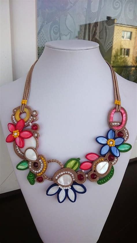 A Necklace With Flowers On It Is Sitting On A Mannequin