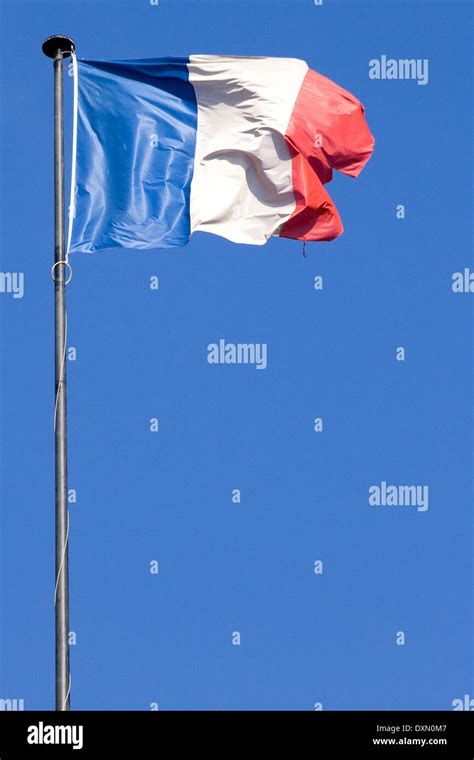 French Flag on a pole on top of a building against a blue sky Paris ...