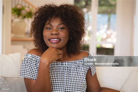 Portrait Of Smiling African American Woman Sitting On Sofa At Home