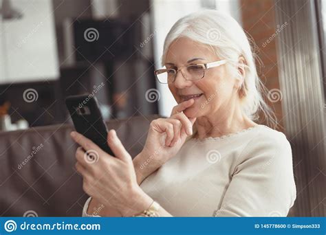 Mulher Superior Bonita Que Texting Em Casa Foto De Stock Imagem De