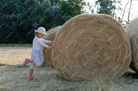 Premium Photo | A little girl next to a big bale of hay