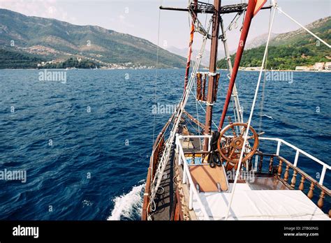 Deck Of A Wooden Ship With A Steering Wheel Sailing On The Sea Stock