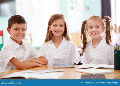 Portrait Of Three Elementary School Pupils Wearing Uniform Using