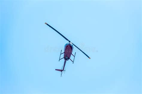 A Small Two Seater Commercial Helicopter Set Against A Clear Blue Sky